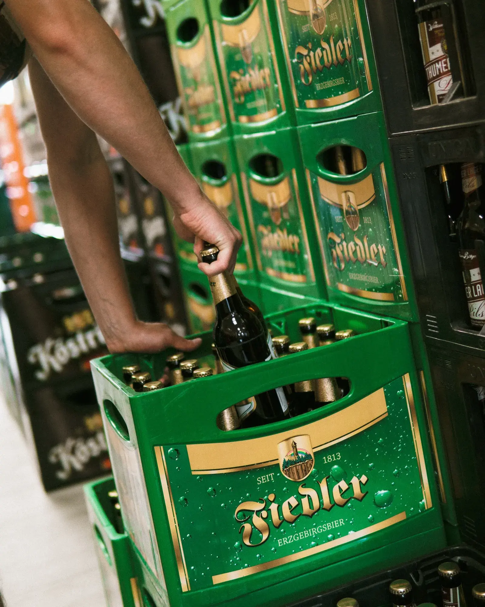 Mitarbeiter hebt eine Flasche aus einem Fiedler-Kasten im Getränkemarkt